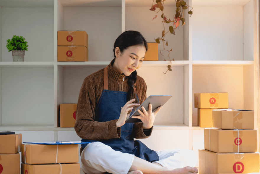 Woman with tablet amid boxes, epitomizing MyGuava's easy 'Business Payments' in EUR, streamlined SEPA transfers, and efficient IBAN management