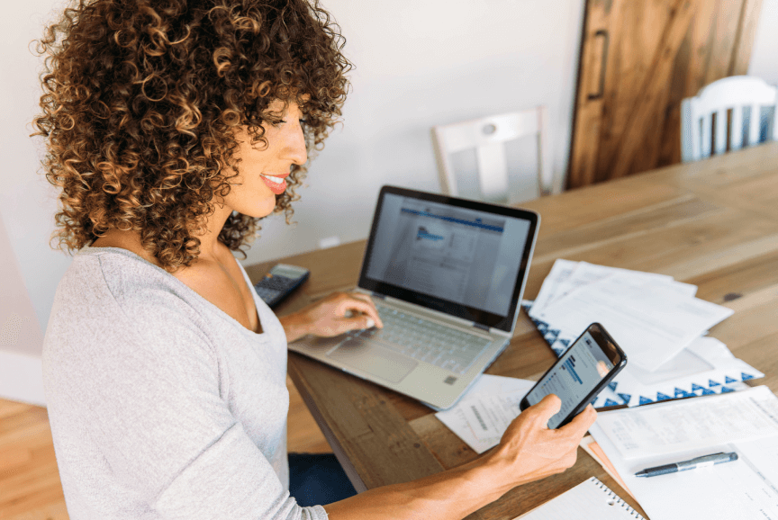 Dedicated female at home with laptop and phone, representing MyGuava's 'Business Payments' for effortless recurring transactions and time-saving
